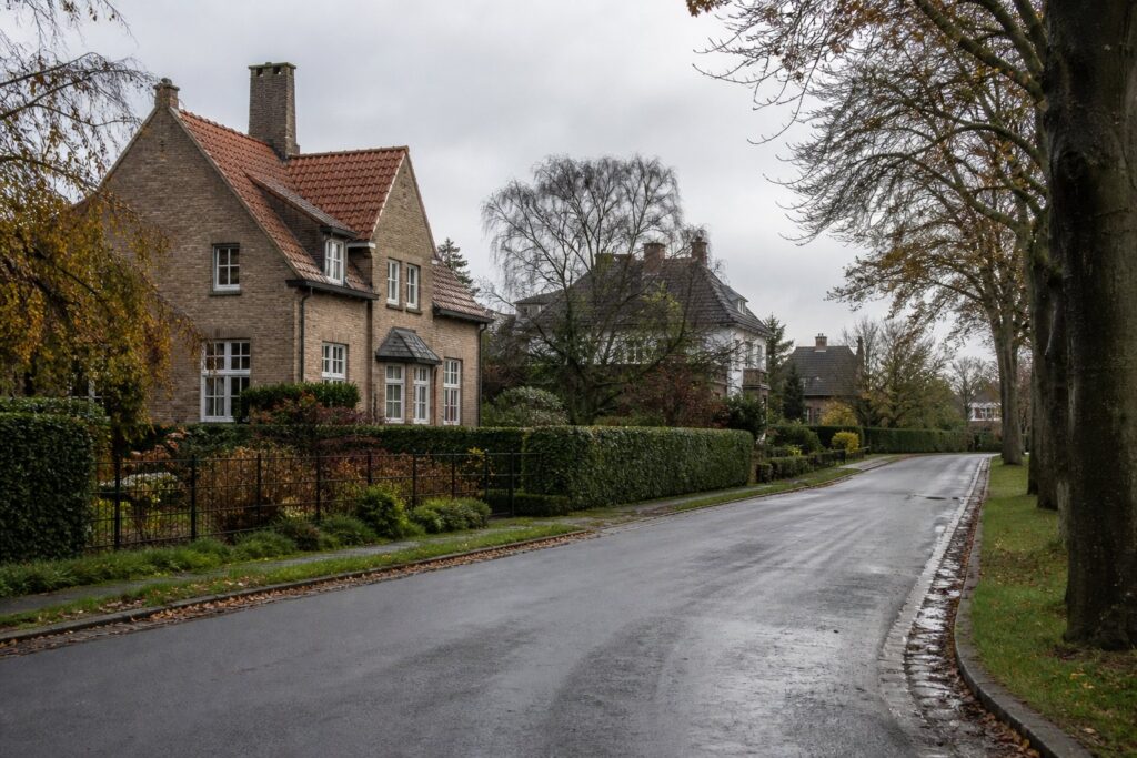 Rustige Vlaamse woonstraat met vrijstaande bakstenen villas achter hagen en grote voortuinen